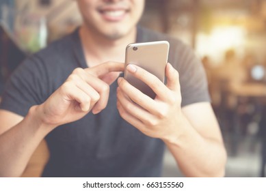 Happy man using smartphone at modern coffee shop, he chatting Online Messaging on mobile phone. - Shutterstock ID 663155560