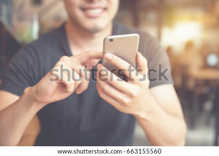 Happy man using smartphone at modern coffee shop, he chatting Online Messaging on mobile phone.