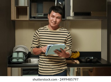 happy man using tablet computer in the kitchen