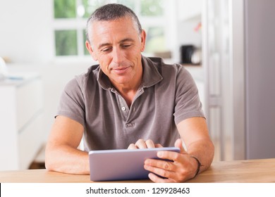 Happy Man Using Tablet At Kitchen Table