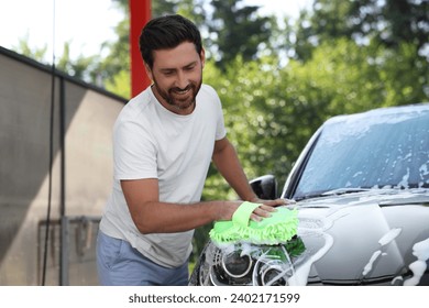 Happy man washing car with sponge outdoors - Powered by Shutterstock