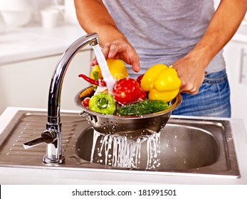Happy man washing fruit at kitchen.