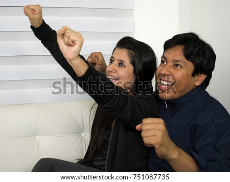 Happy man watching television with his girlfriend sitting on the sofa at home