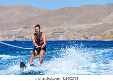 Happy man waterskiing and having fun. Living a healthy lifestyle and staying active. Doing water sports in the summer on a holiday in Greece.