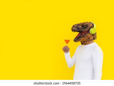 Happy man wearing dinosaur head mask with martini glass in hand and red beverage. - Powered by Shutterstock