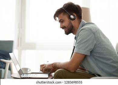 Happy Man Wearing Headset Study Online Learning Foreign English Language Or Watch Webinar Make Notes, Smiling Male Student In Headphones Looking At Laptop Elearning In Internet Write Down Information