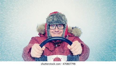 Happy Man in winter clothes with a steering wheel, snow blizzard. Concept car driver.