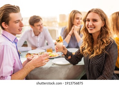 Happy man and woman with alcohol drinks smiling while sitting at table during meeting with friend