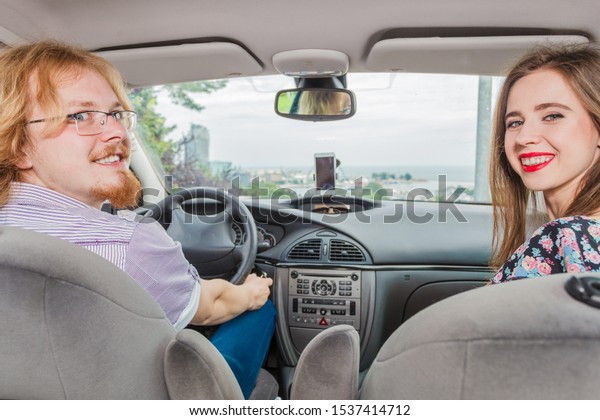 Happy man and woman\
during traveling trip. Couple, friends sitting inside vehicle car\
driving riding somewhere.
