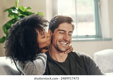 Happy man, woman and kiss on cheek on sofa for love, affection and proud for engagement. Interracial couple, hug and commitment in relationship with good news, trust and support at home with care - Powered by Shutterstock