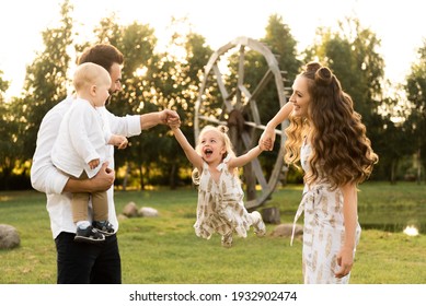 Happy man and woman play with children outside on a sunny day