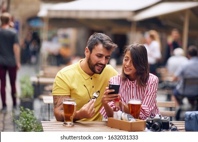 Happy Man And Woman Of Tourists Checking Location On Phone At Caffe.