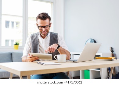 Happy Man Working From Home Using Digital Tablet And Laptop