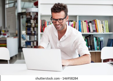 Happy Man Working On Laptop In Library