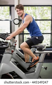 Happy Man Working Out On Exercise Bike At Spinning Class In Gym