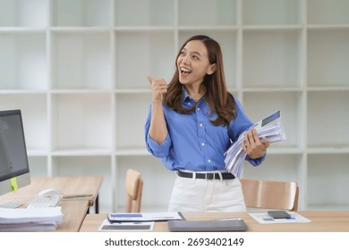 Happy manager showing thumbs up while holding documents, expressing her satisfaction with successful work in the office