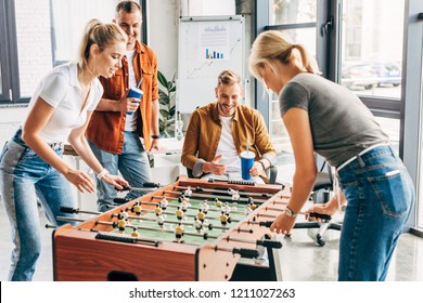 Happy Managers Playing Table Football At Office And Having Fun Together