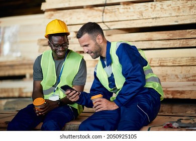 Happy manual workers enjoying in coffee break and using mobile phone at wood distribution warehouse. - Powered by Shutterstock