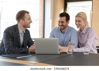 Happy Married Clients Consulting Real Estate Agent In His Office. Realtor Showing Online Virtual Tour In House On Laptop To Buyers At Meeting In Agency. Couple Choosing Apartment For Rent, Buying