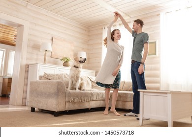 Happy married couple a charming girl and tall man are dancing their new living room of their small country house recently bought along with their beloved dog - Shutterstock ID 1450573718