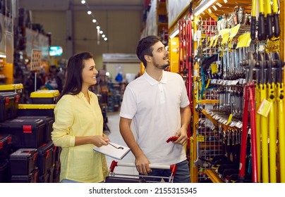 Happy married couple chooses variety of tools and materials for repairs in apartment. Young husband and wife are looking at goods on shelves of large warehouse hypermarket of building materials. - Shutterstock ID 2155315345