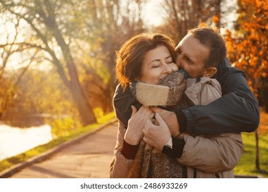 happy married couple over 50 years old, walking in the park in autumn on a warm sunny day, hugging, spending a day off together. - Powered by Shutterstock