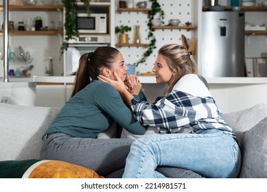 Happy Married Homosexual Female Gay Couple Laughing And Embracing On The Sofa With Smile On Their Faces. Lesbian Couple At Home Enjoying Life Together In Their New Apartment.