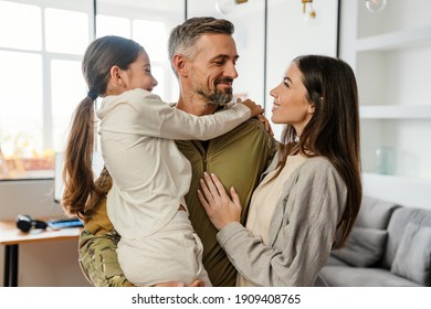 Happy Masculine Military Man Smiling And Hugging His Family Indoors