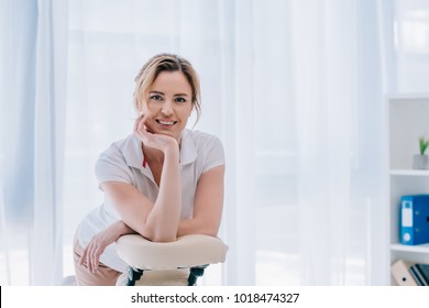 happy massage therapist leaning on chair for seated massage - Powered by Shutterstock