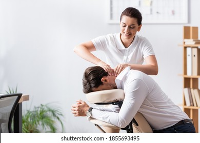 Happy masseuse doing neck massage for businessman in office on blurred background - Powered by Shutterstock