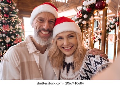 Happy mature 50 years old grandparents couple in santa hats waving hands greeting family on distance video call, having remote online virtual xmas party meeting on Christmas at home. Webcam view - Powered by Shutterstock