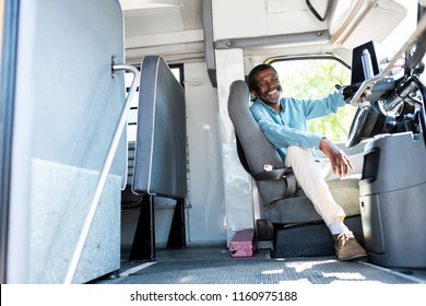 happy mature african american bus driver looking at camera while sitting inside bus