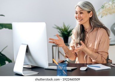 Happy Mature Asian Woman Communicate By Video Call On Computer Working From Home. Smiling Middle Aged Businesswoman Talking By Video Conference, Online Virtual Meeting Using Computer