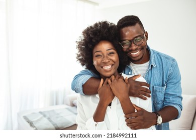 Happy Mature Black Couple Bonding To Each Other And Smiling. Portrait Of Smiling Black Man Embrace His Wife From Behind And Looking At Camera. Portrait Of A Happy Young Couple 