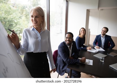 Happy Mature Business Teacher, Coach Giving Workshop To Diverse Team, Explaining Project Presentation, Training New Employees. Middle Aged Female Business Mentor Having Fun With Intern Group