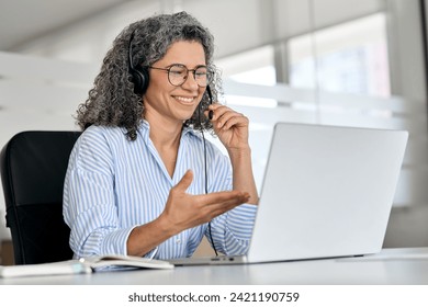 Happy mature business woman call centre representative customer support agent talking to client, smiling middle aged senior female operator wearing headset working using laptop computer in office. - Powered by Shutterstock