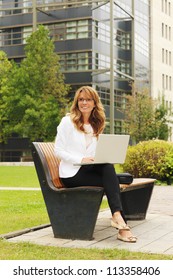 A Happy Mature Business Woman Working On Her Laptop Outside In The Park