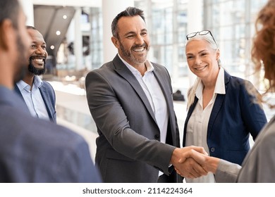 Happy mature businessman shaking hands with businesswoman in modern office. Successful entrepreneur greeting business woman with handshake. Agreement and business deal concept. - Shutterstock ID 2114224364