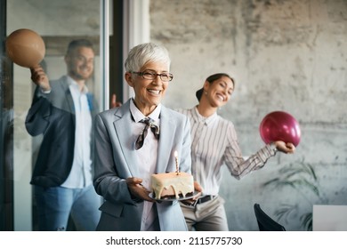 Happy Mature Businesswoman And Her Co-workers Having Fun On Surprise Birthday Party In The Office.