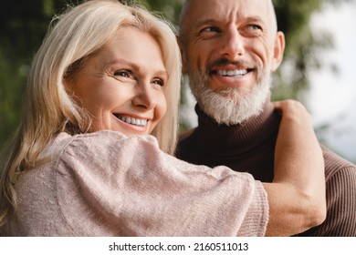 Happy mature caucasian couple wife and husband spouses hugging embracing looking at the same direction together. Bonding, hoping for future.