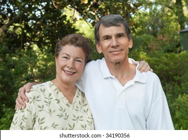 Happy Mature Couple, Arms Around Each Other Outdoors.