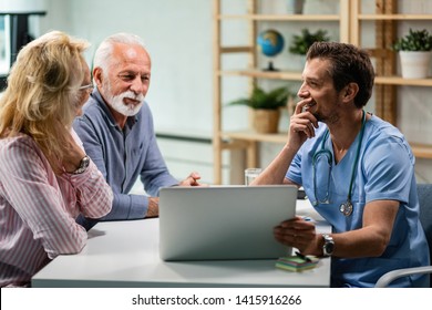 Happy mature couple communicating with their doctor while using laptop together. Focus is on doctor. 