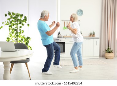 Happy Mature Couple Dancing Together In Kitchen