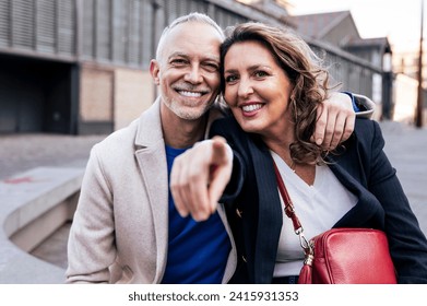 Happy mature couple embracing and looking at each other walking together. Affectionate mid adult man and woman standing and holding arms in the street. - Powered by Shutterstock