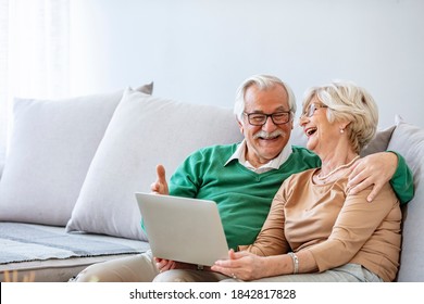 Happy Mature Couple Having A Video Chat Over Laptop At Home. Side View Of Senior Caucasian Couple Interacting With Each Other While Using Laptop At Retirement Home