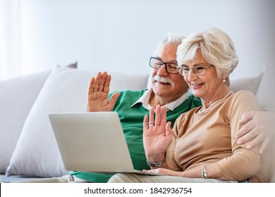 Happy Mature Couple Having A Video Chat Over Laptop At Home. Side View Of Senior Caucasian Couple Interacting With Each Other While Using Laptop At Retirement Home