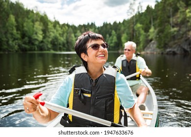 Glückliches reife Paar in lebendigen Westen Kanu in Wald See. Sonniger Sommertag. Touristen reisen in Finnland, mit Abenteuer. 