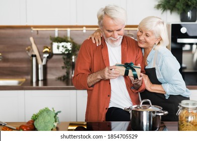 Happy mature couple in love. Caring wife gives a gift to her beloved husband - Powered by Shutterstock
