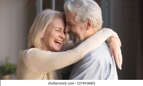 Happy mature couple in love embracing, laughing grey haired husband and wife with closed eyes, horizontal banner, middle aged smiling family enjoying tender moment, happy marriage, sincere feelings