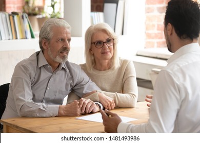 Happy mature couple meeting with male real estate agent or broker discuss future property purchase contract terms, excited pensioner husband and wife talk with financial consultant taking loan